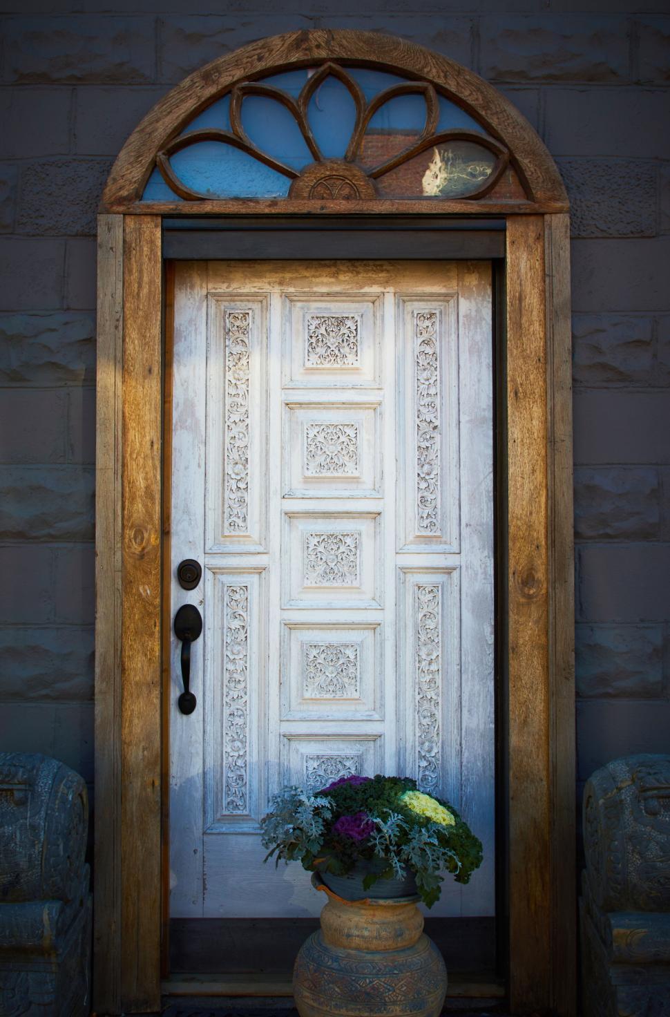 Free Image of Ornate rustic door with flower pot in front of building 