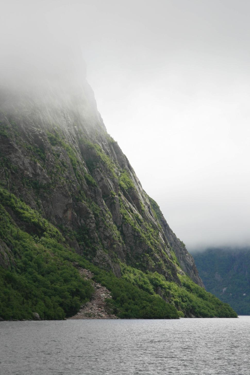 Free Image of Majestic mountain peaks covered in mist above a lake. 