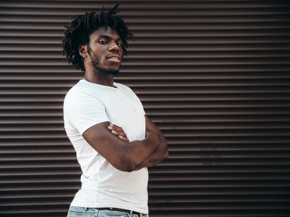 Free Image of Man crossing arms standing in front of dark background 