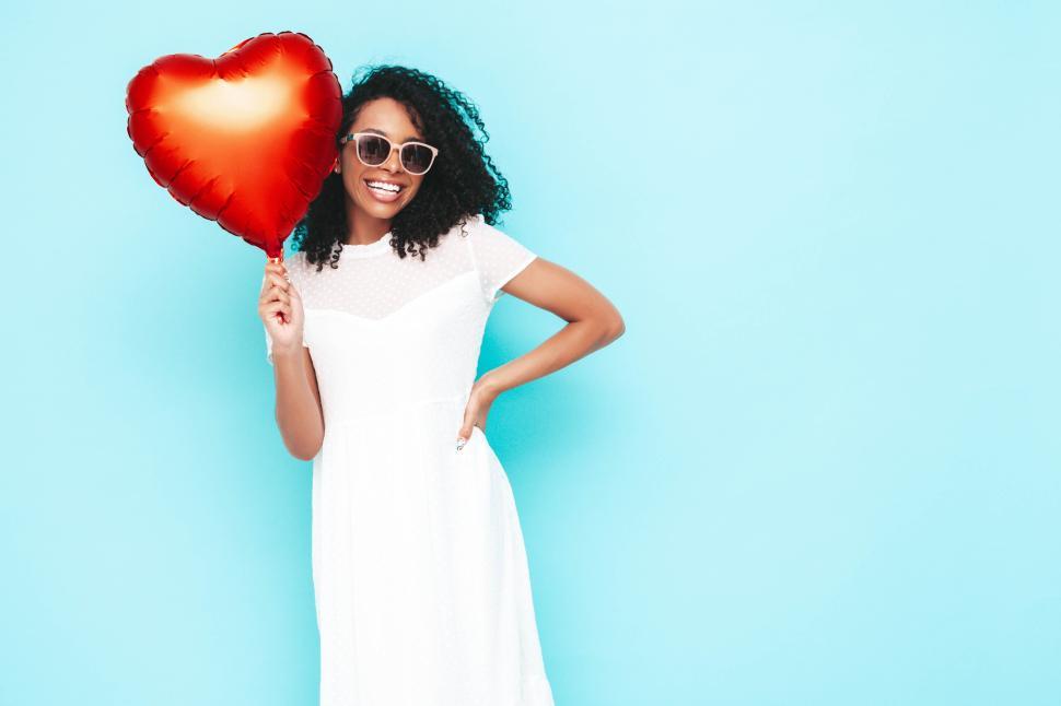 Free Image of Woman in white dress holding heart-shaped red balloon 