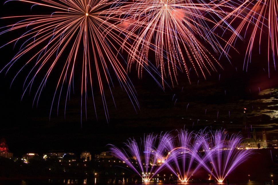 Free Image of Red and purple fireworks over cityscape in night sky. 