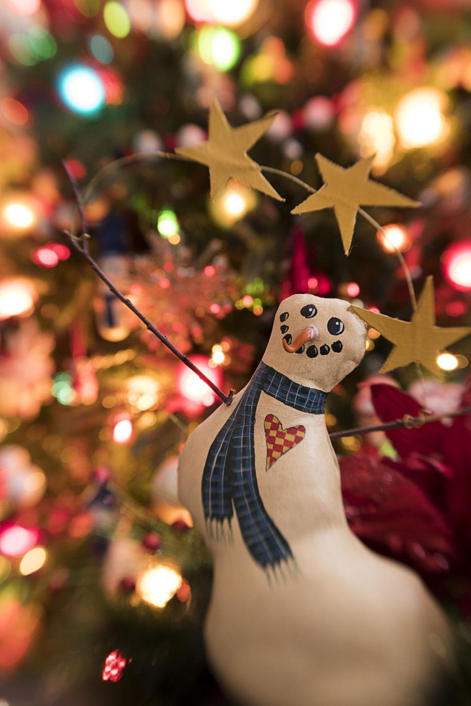 Free Image of Handmade snowman ornament on a festive Christmas tree. 