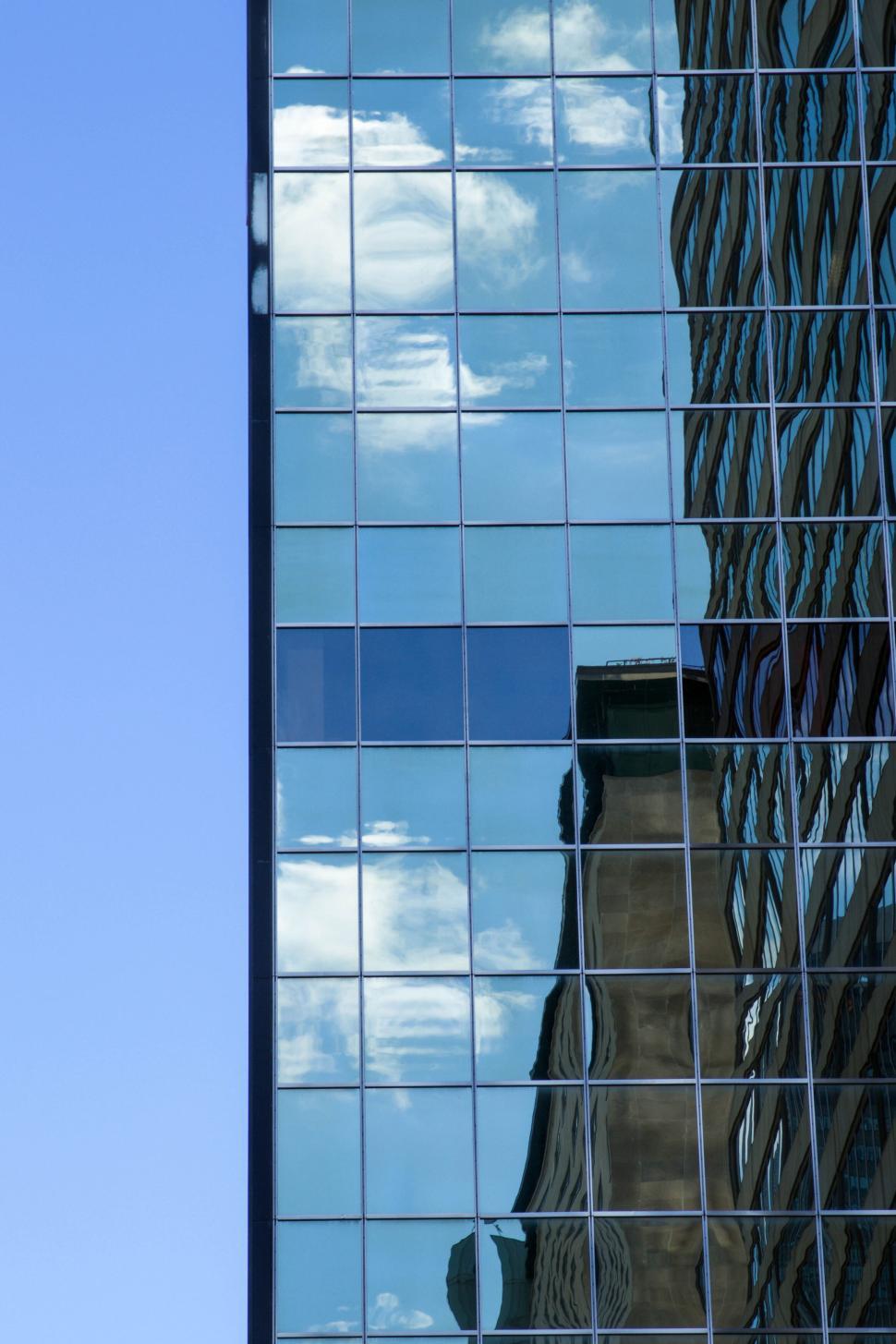Free Image of Glass building reflecting the blue sky and clouds 