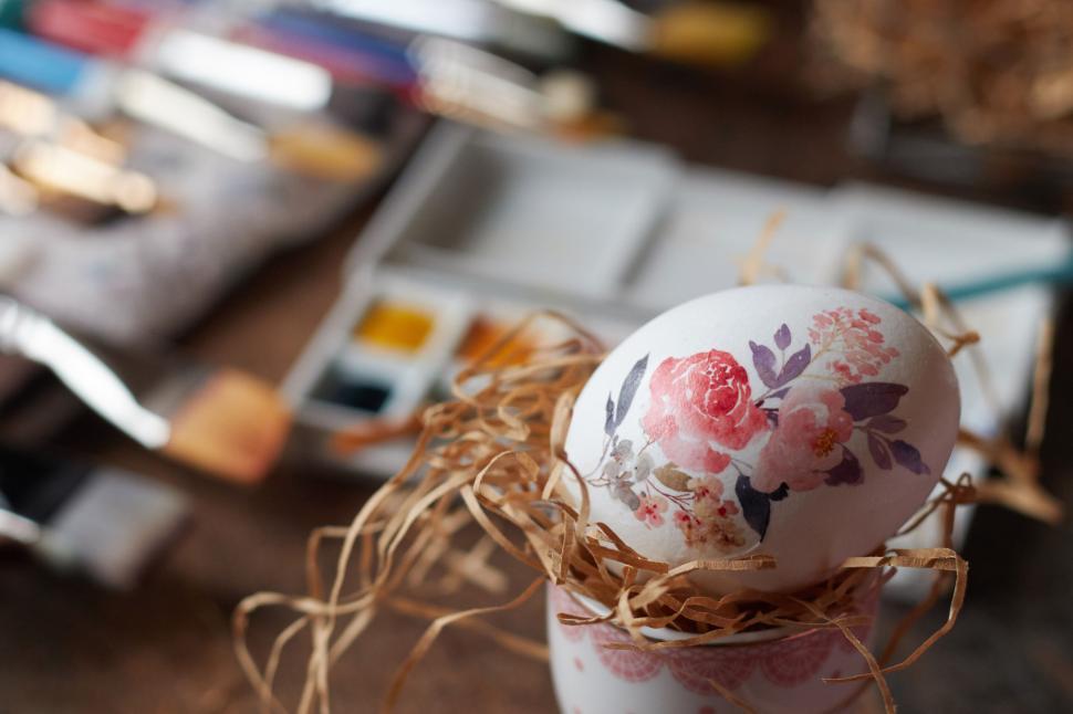 Free Image of Decorated egg in a nest with artistic tools nearby 
