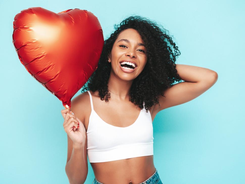 Free Image of Woman holding heart balloon in white top with big smile 