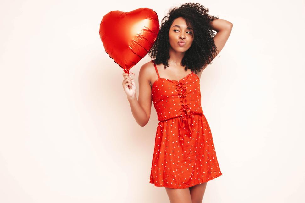 Free Image of Woman with red dress and heart balloon posing cheerfully 