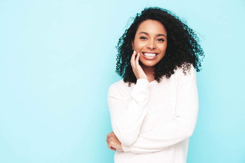 Free Image of Smiling woman with hand on chin against blue background. 