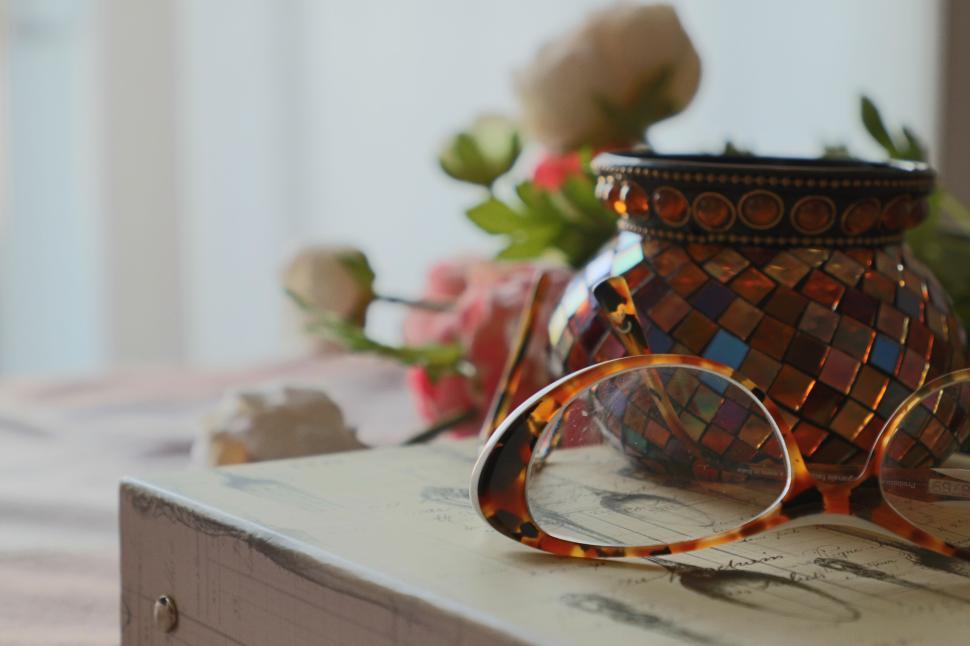 Free Image of Vintage glasses on book with colorful mosaic candle jar 