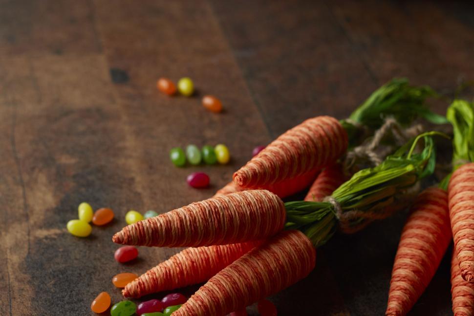 Free Image of Bunch of carrots on wooden table with scattered candies 