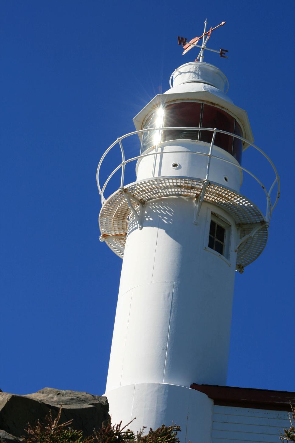 Free Image of White lighthouse with clear blue sky and wind vane 