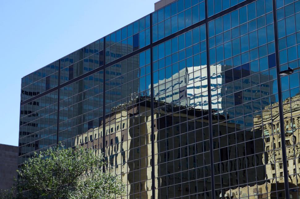 Free Image of Modern glass building reflecting surrounding urban scene 