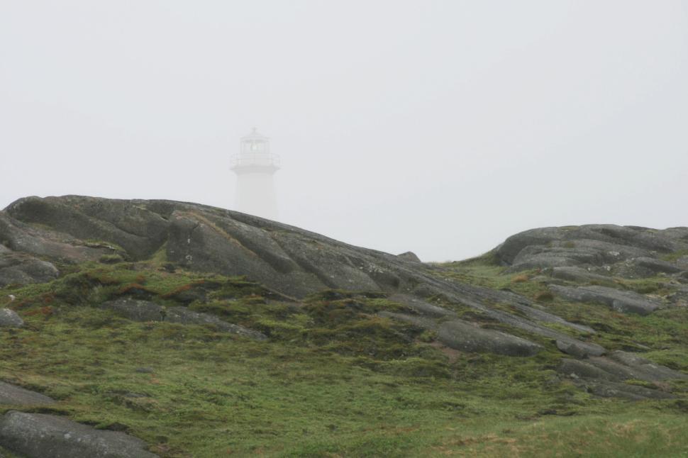 Free Image of Lighthouse in the distance partially hidden by misty fog 