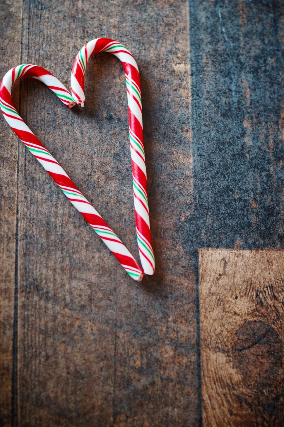 Free Image of Heart-shaped candy canes on a rustic wooden background 