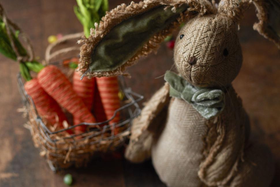 Free Image of Cute rustic bunny toy with basket of carrots on wood table. 