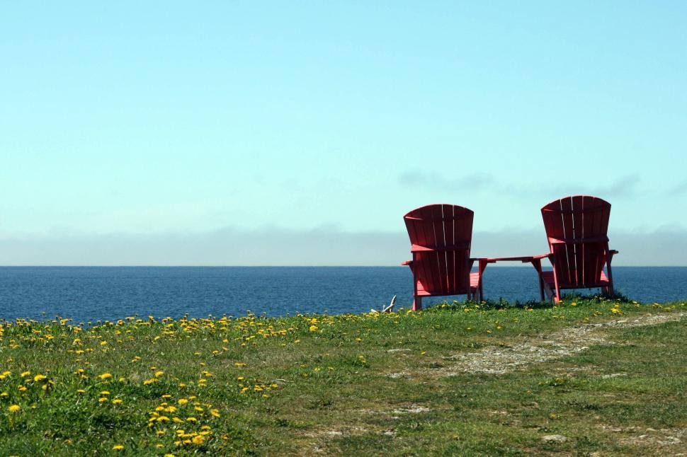 Free Image of Two red chairs facing the vast blue sea and sky. 