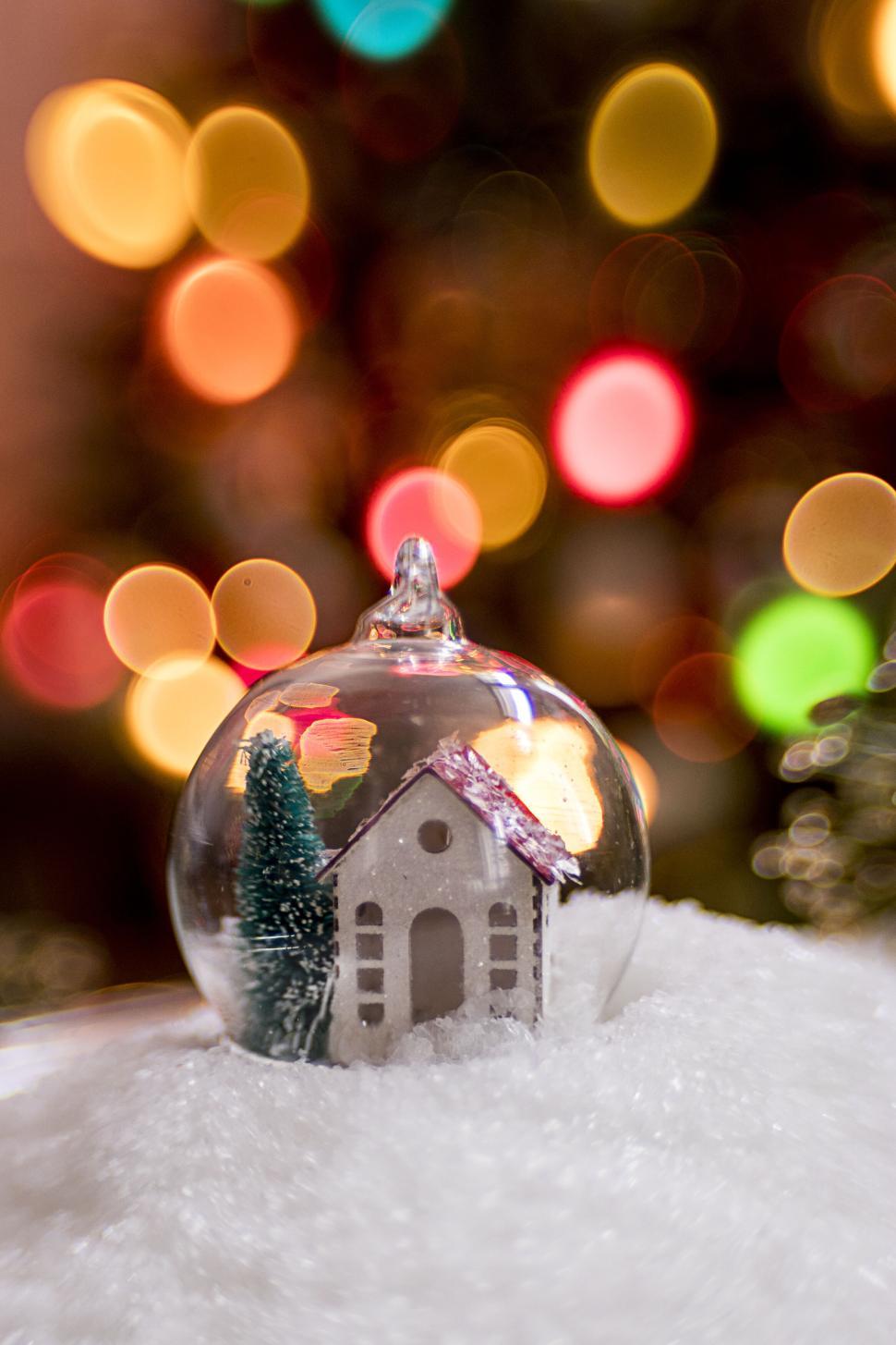 Free Image of Snow globe with a small house and festive bokeh lights 