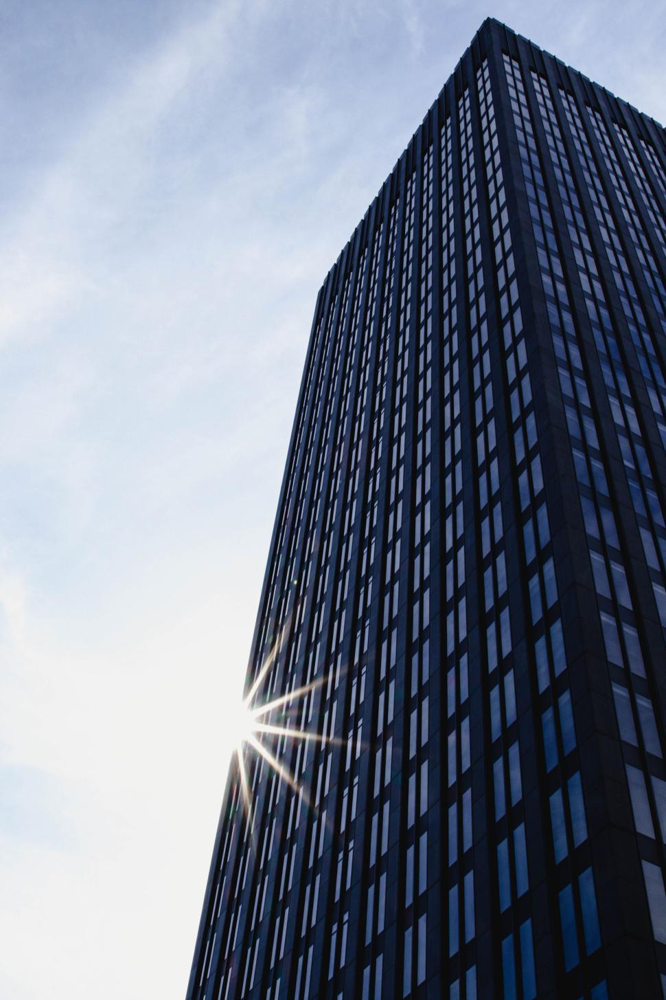 Free Image of Tall modern skyscraper with sun reflecting on windows 