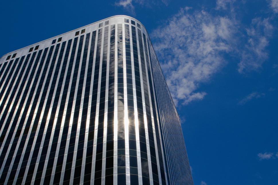 Free Image of Modern glass skyscraper against blue cloudy sky. 