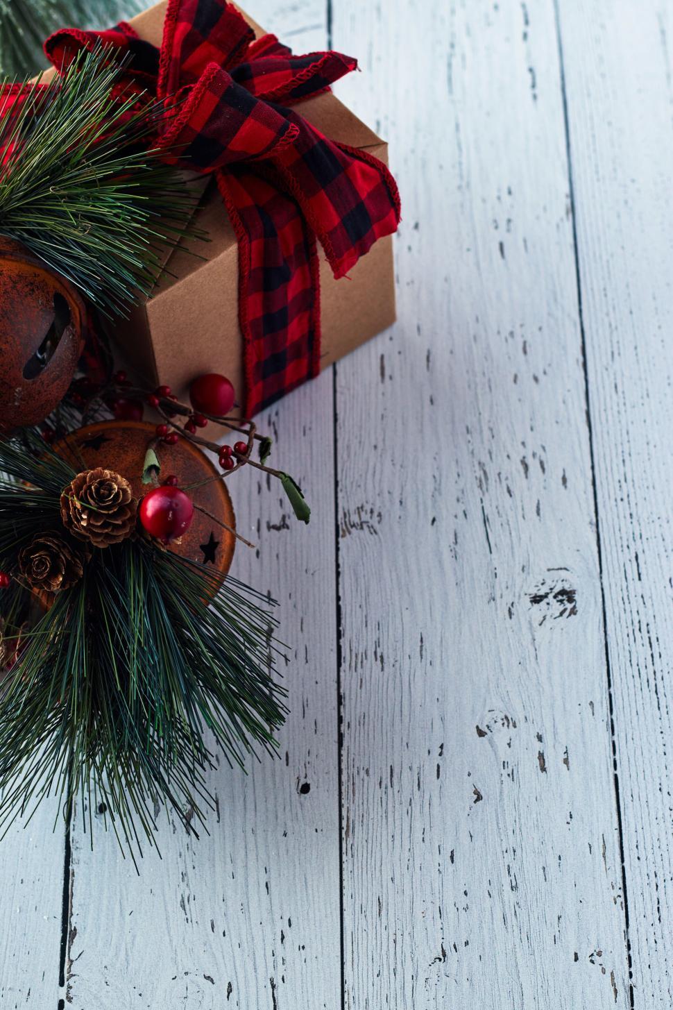 Free Image of Festive gift wrapped in plaid ribbon with pine decor. 