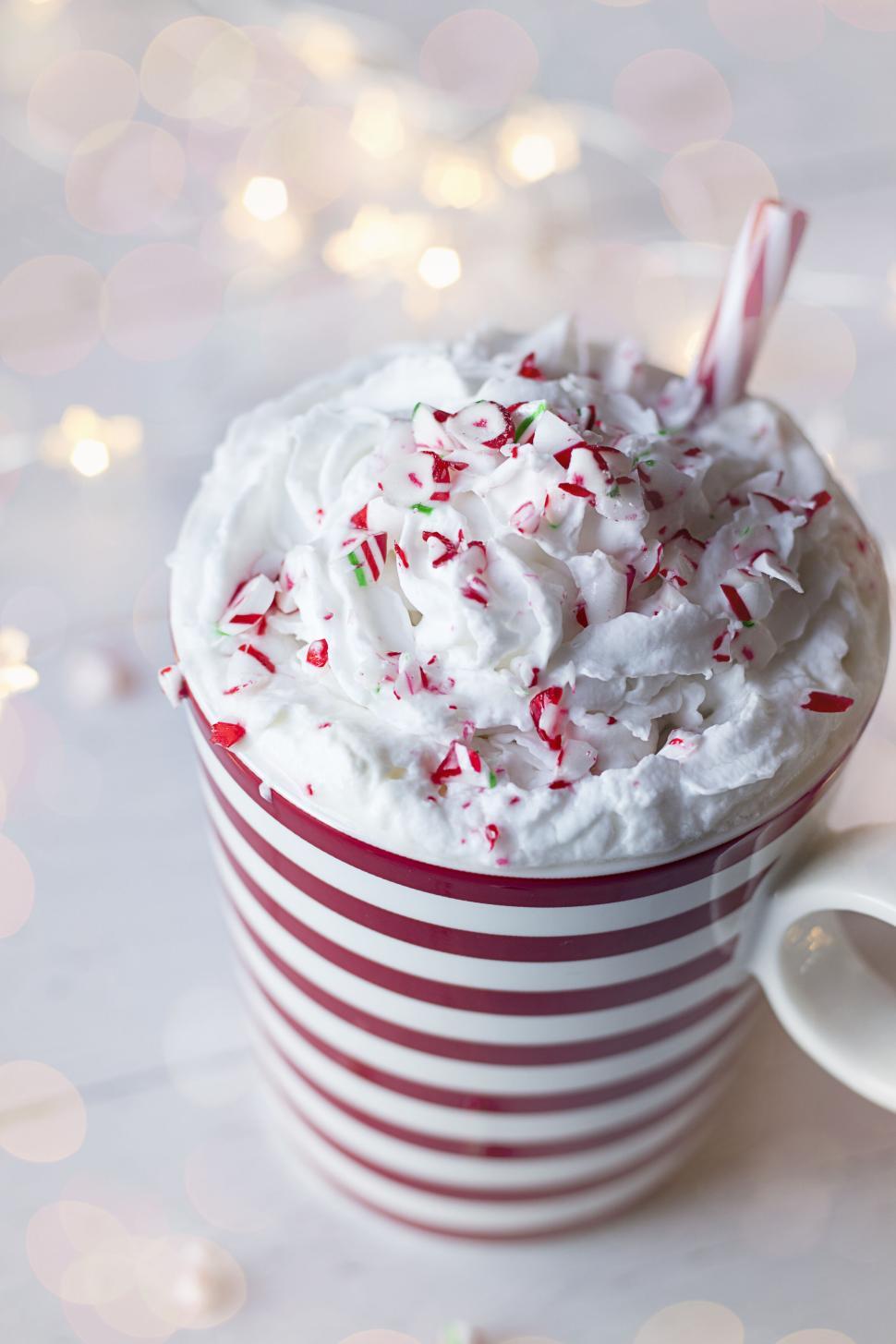 Free Image of Whipped cream topped hot chocolate in a festive striped mug. 