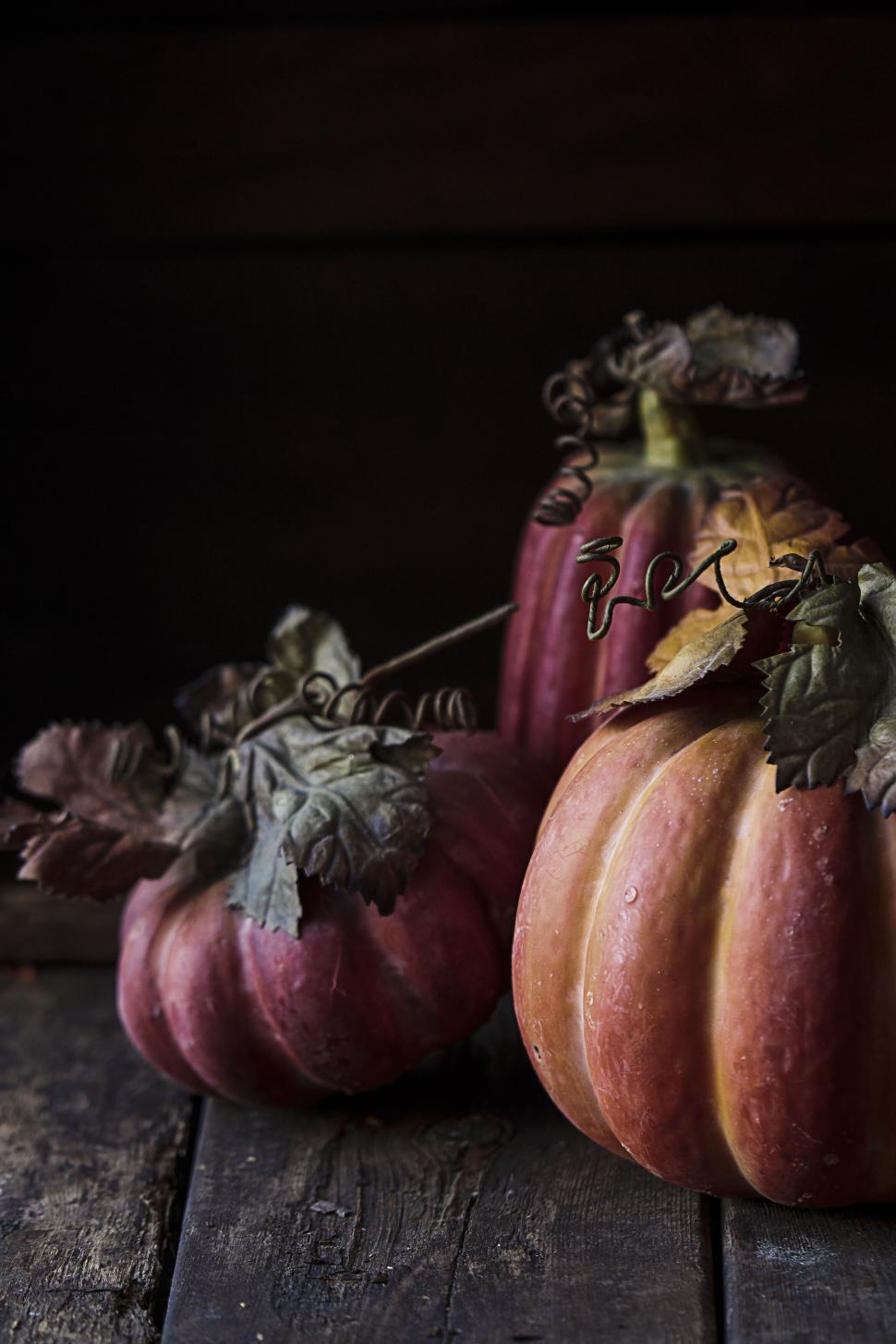 Free Image of Rustic pumpkins with leaves on wooden table in darkness 