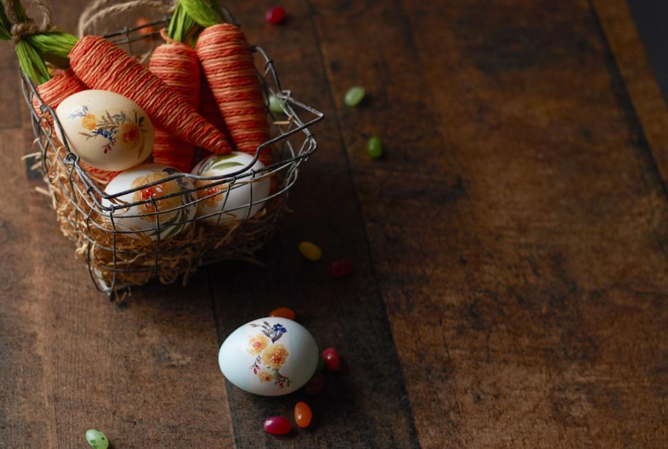 Free Image of Decorated Easter eggs and cute carrots in wire basket. 