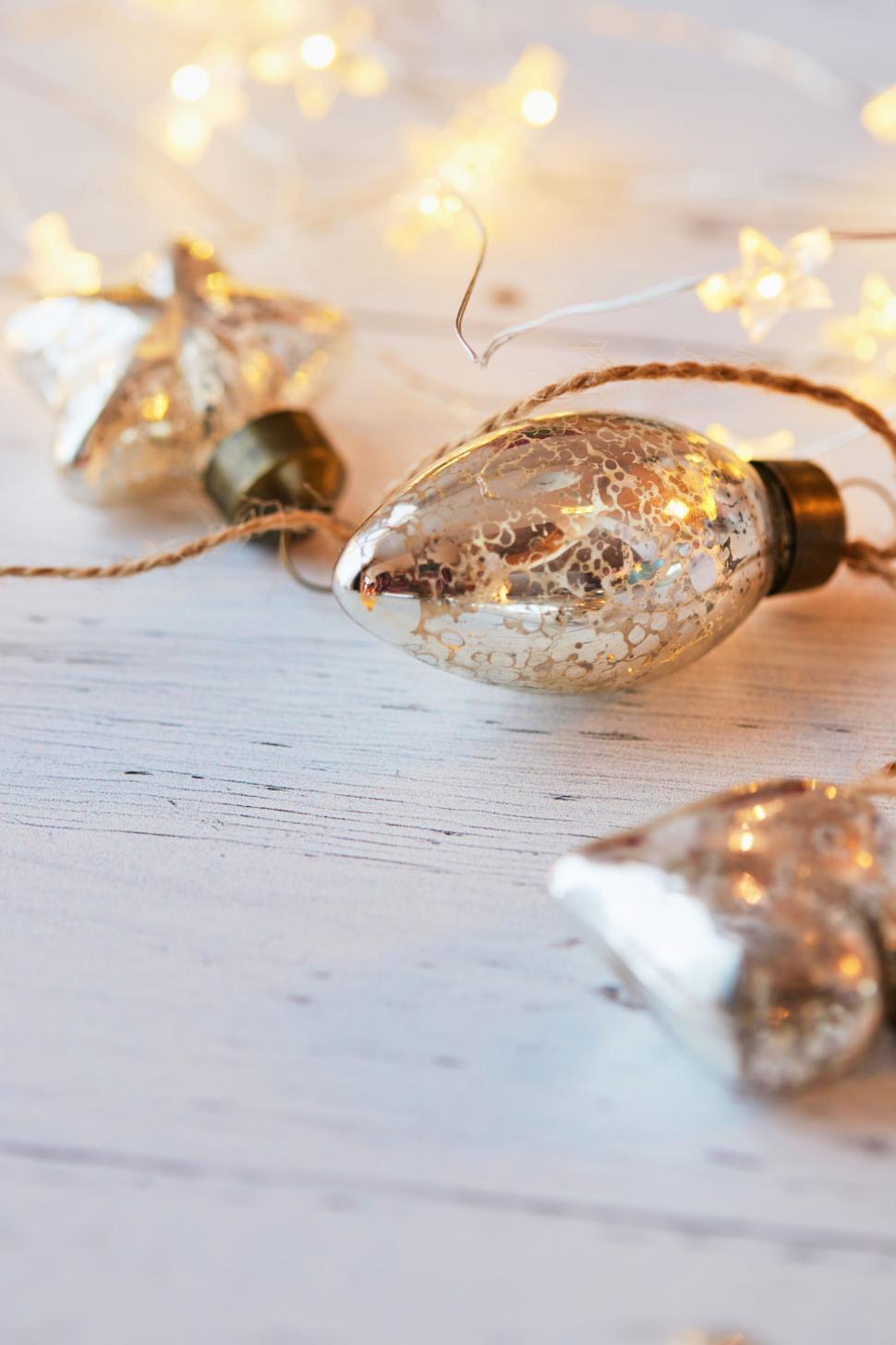 Free Image of Golden Christmas lights with delicate ornaments on twine. 