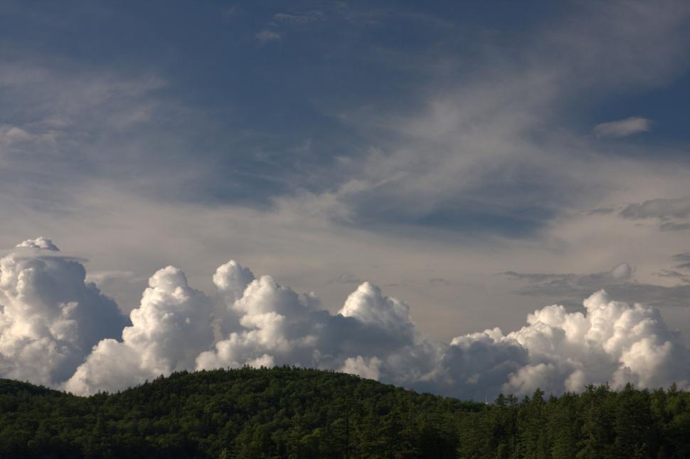 Free Image of Lush green hills under a striking sky with clouds. 