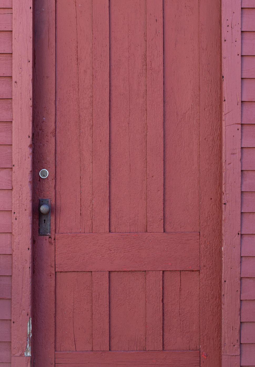 Free Image of Red wooden door on old building with visible textures 