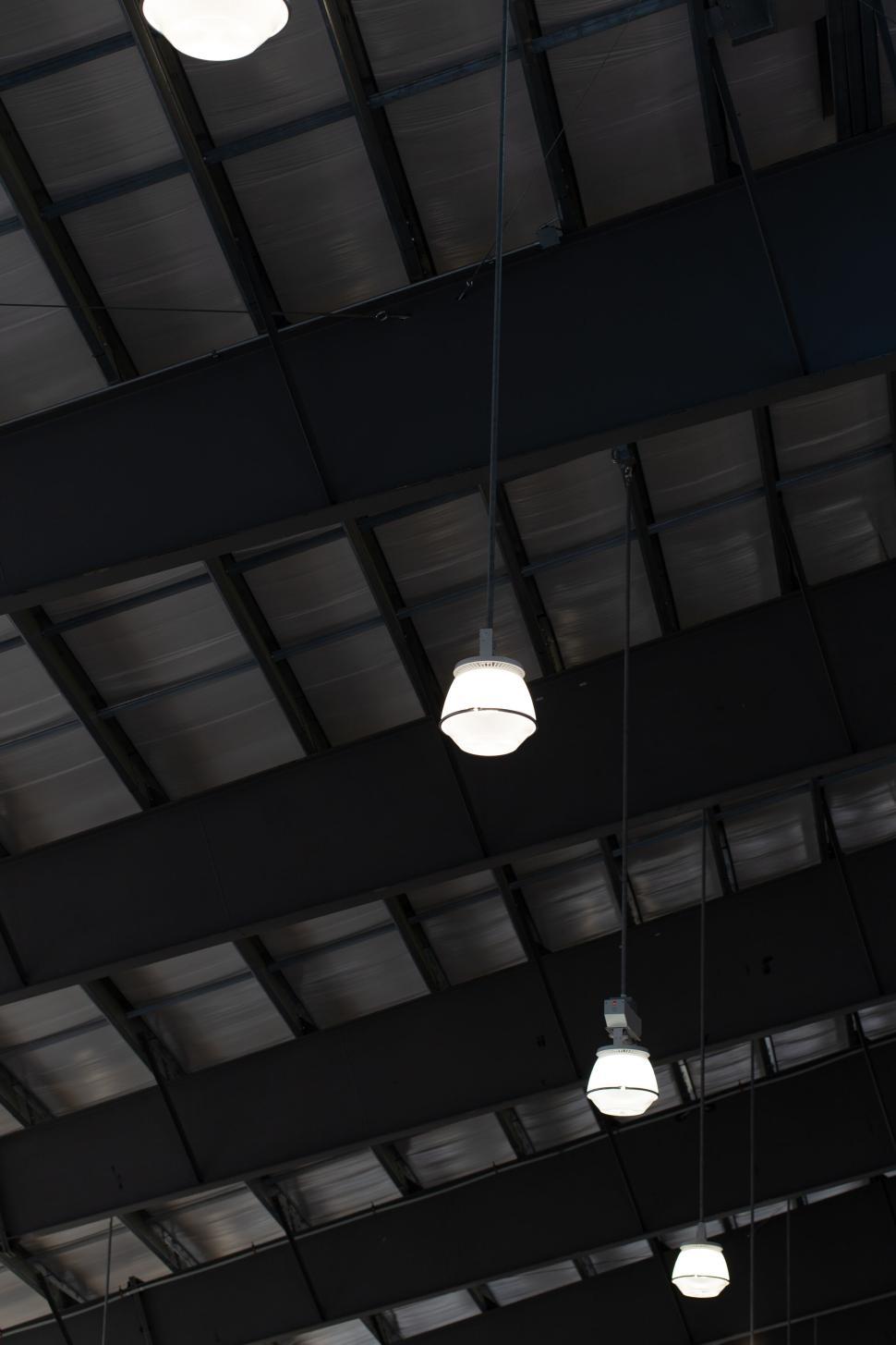 Free Image of Hanging industrial lights on ceiling of large warehouse. 