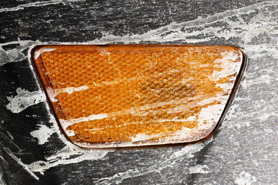 Free Image of Dusty orange car reflector with distinct textured detail. 