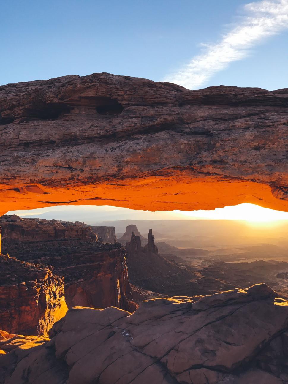 Free Image of Sunrise through natural rock arch in desert landscape 