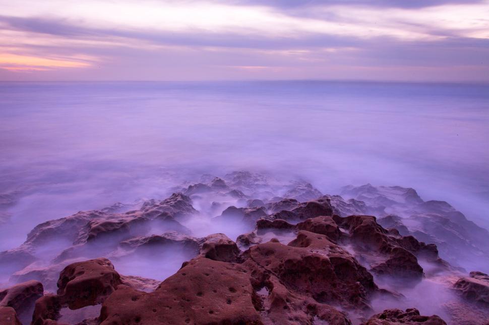 Free Image of Purple twilight over rocky coast with soft waves 