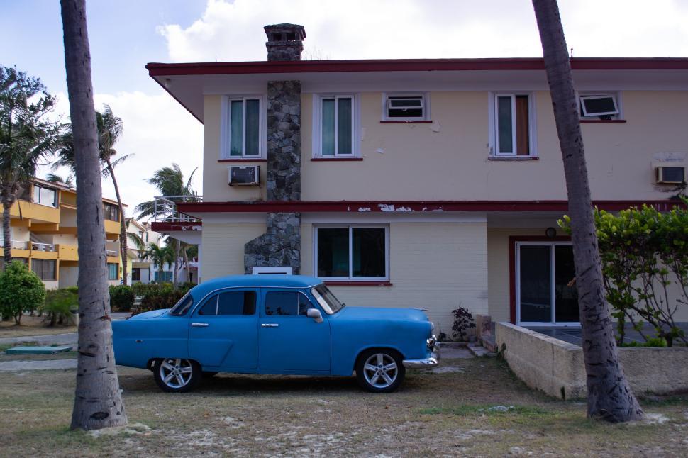 Free Image of Vintage blue car parked by a house under the clear sky. 