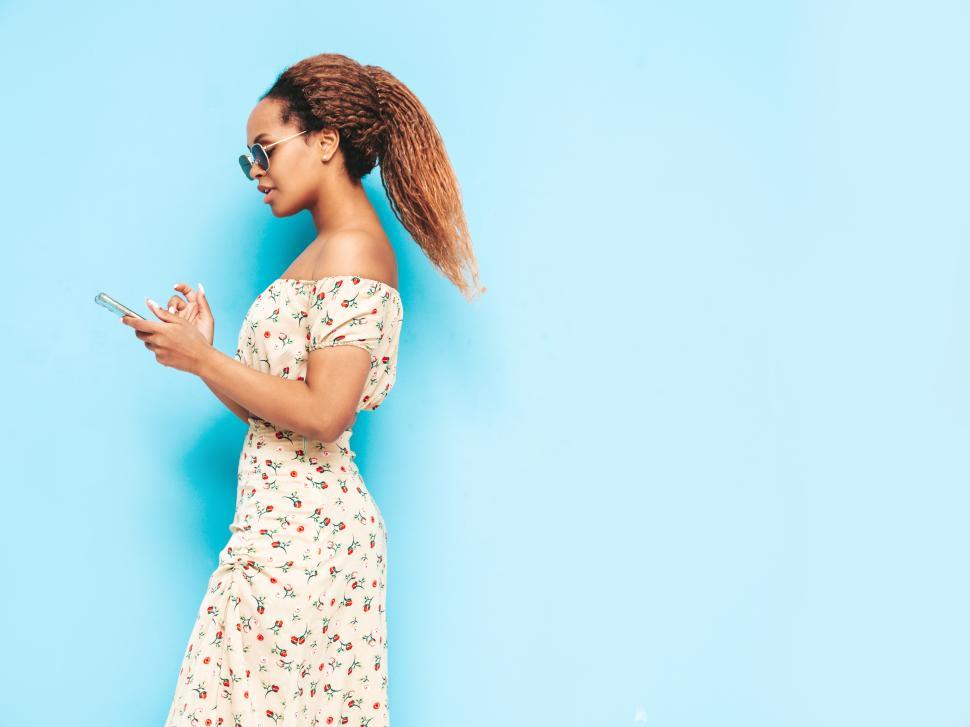Free Image of Person in floral dress using smartphone, blue background. 