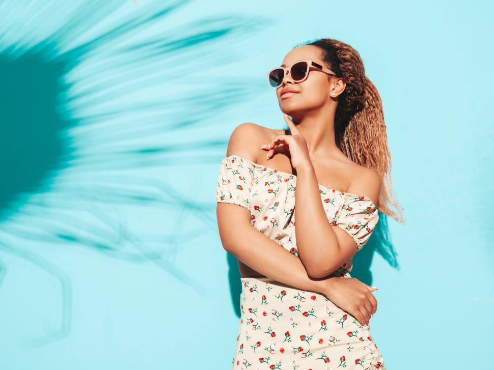 Free Image of Woman posing against a blue background in sunlight. 