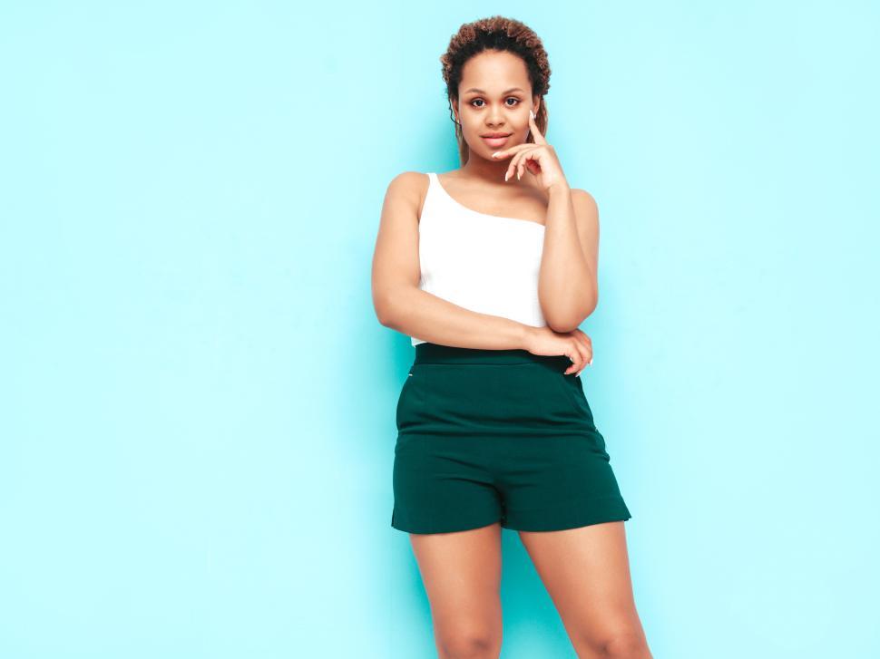 Free Image of Woman in white top and green shorts, poised. 