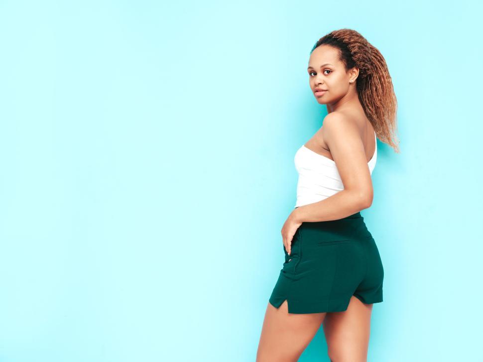 Free Image of Woman in white top and green shorts looks behind. 