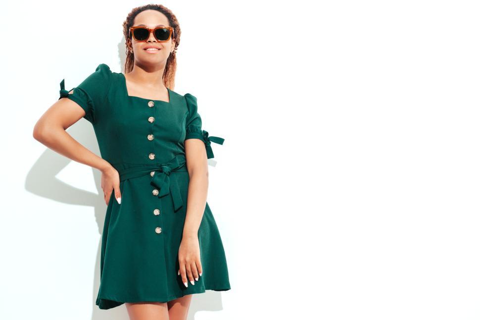 Free Image of Smiling woman wearing green dress and sunglasses outside. 