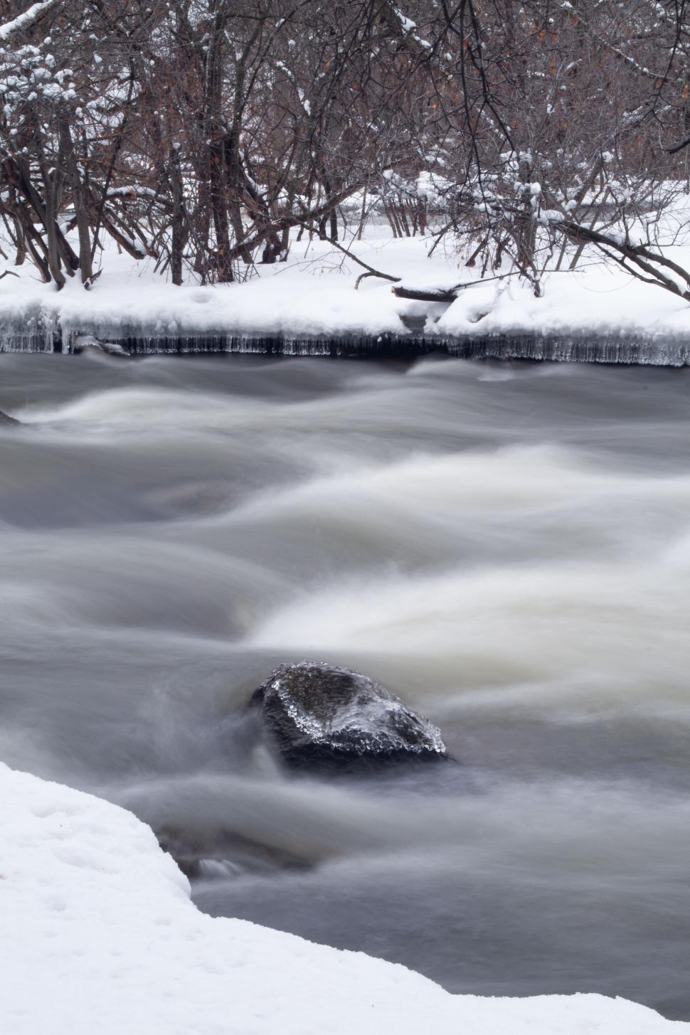Free Image of Snow-covered river flowing through a winter forest 