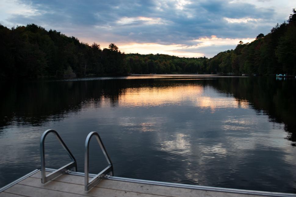 Free Image of Serene lake scene with pier and reflective sunset 