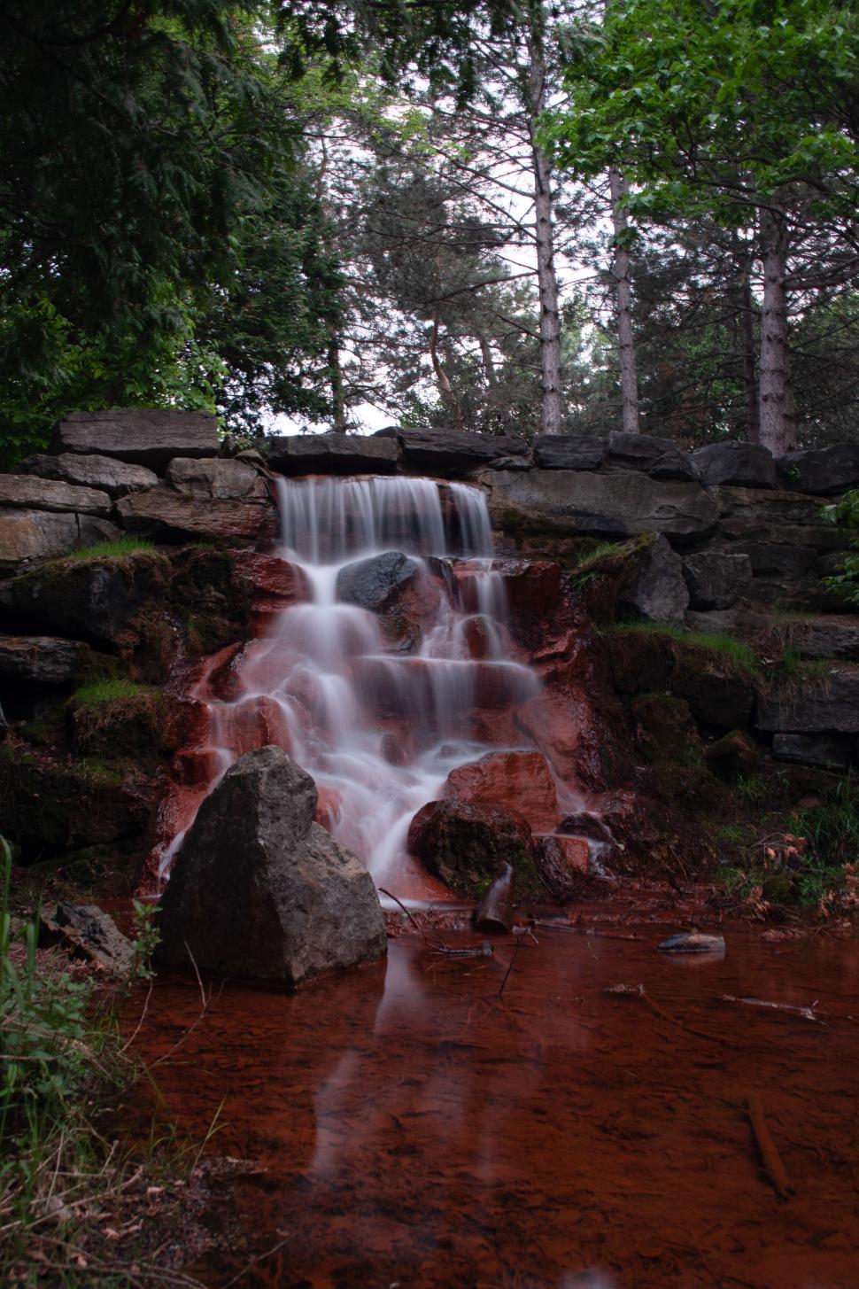 Free Image of A small serene waterfall in a lush green forest 