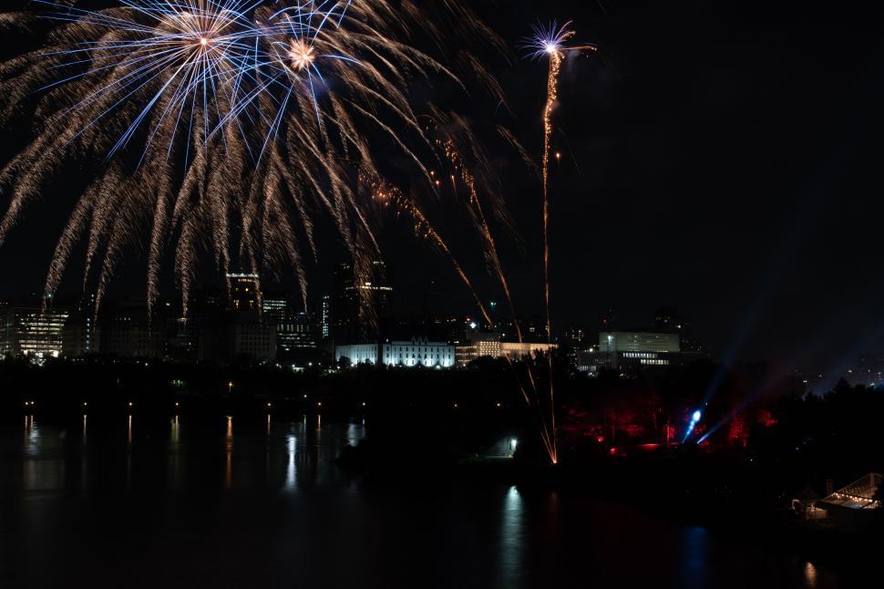 Free Image of Fireworks over city skyline by night with reflections. 