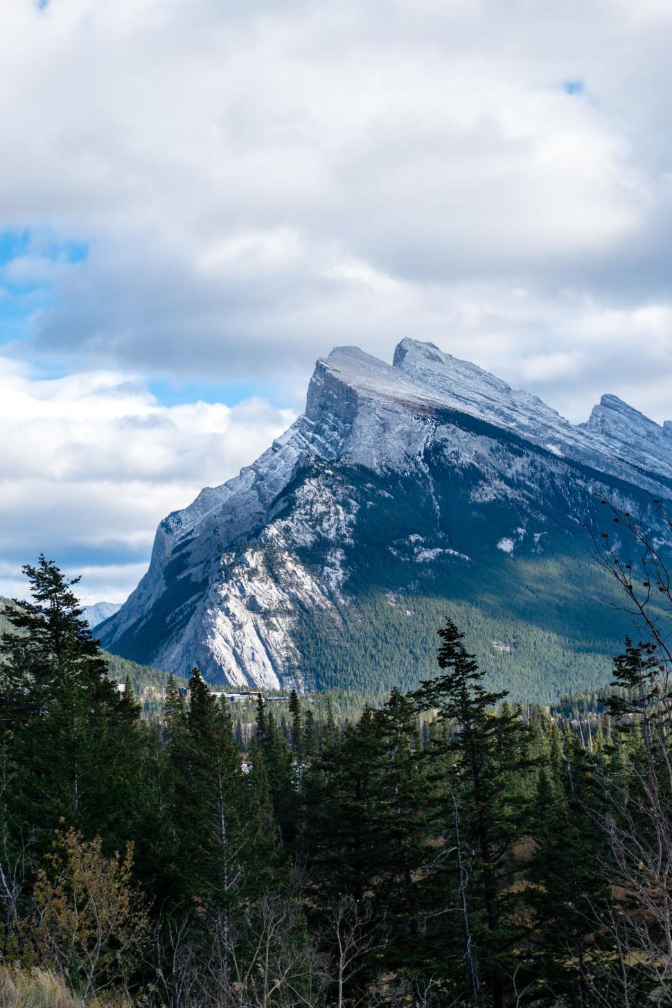 Free Image of Rugged mountain peak with sky and treeline below. 