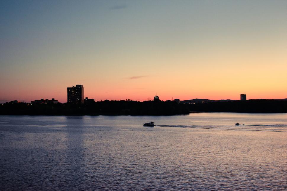 Free Image of Boats cruising during twilight over calm urban waterway 