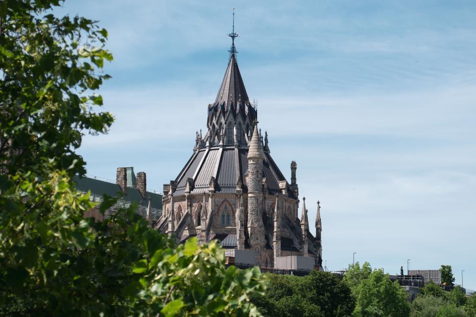Free Image of Ancient Gothic-style building surrounded by green foliage. 