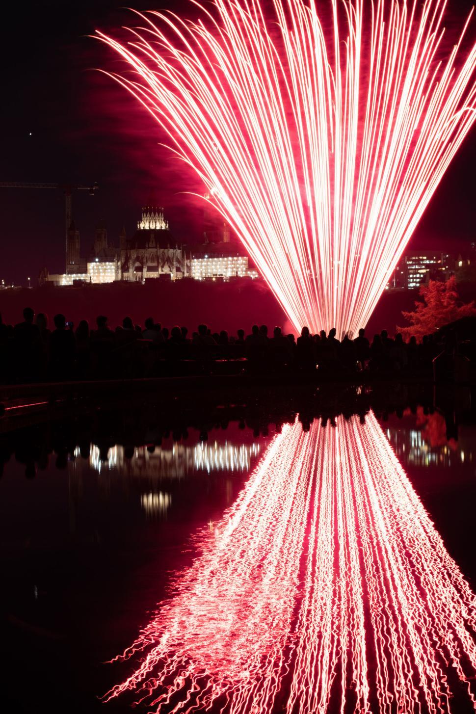 Free Image of Red fireworks lighting up the night sky with reflection 