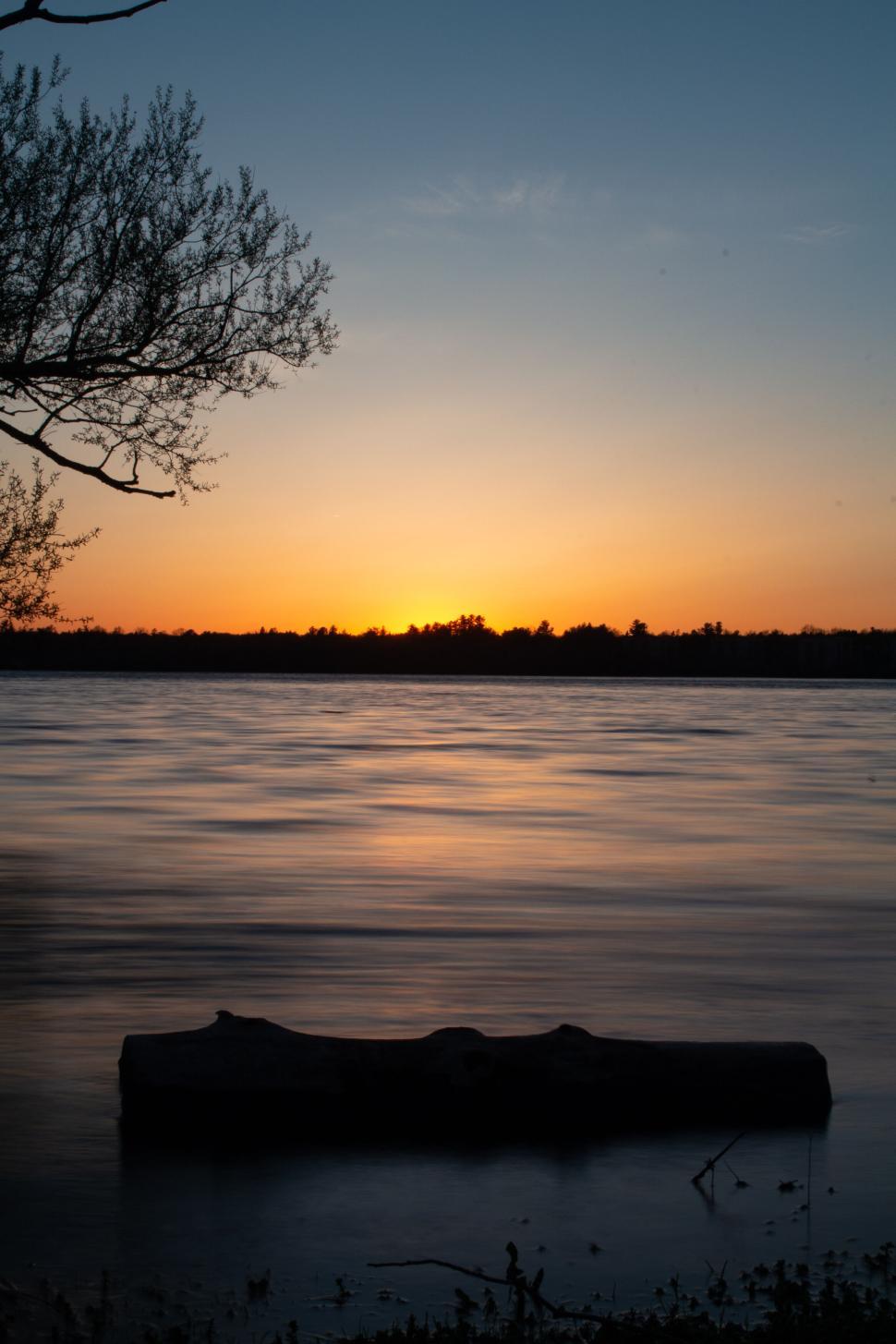 Free Image of Sunset over a calm lake reflecting stunning colors 