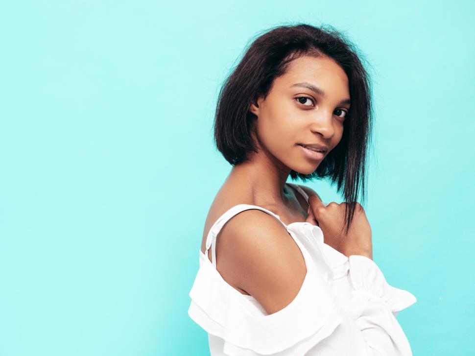 Free Image of Woman in white top posing against a blue background. 