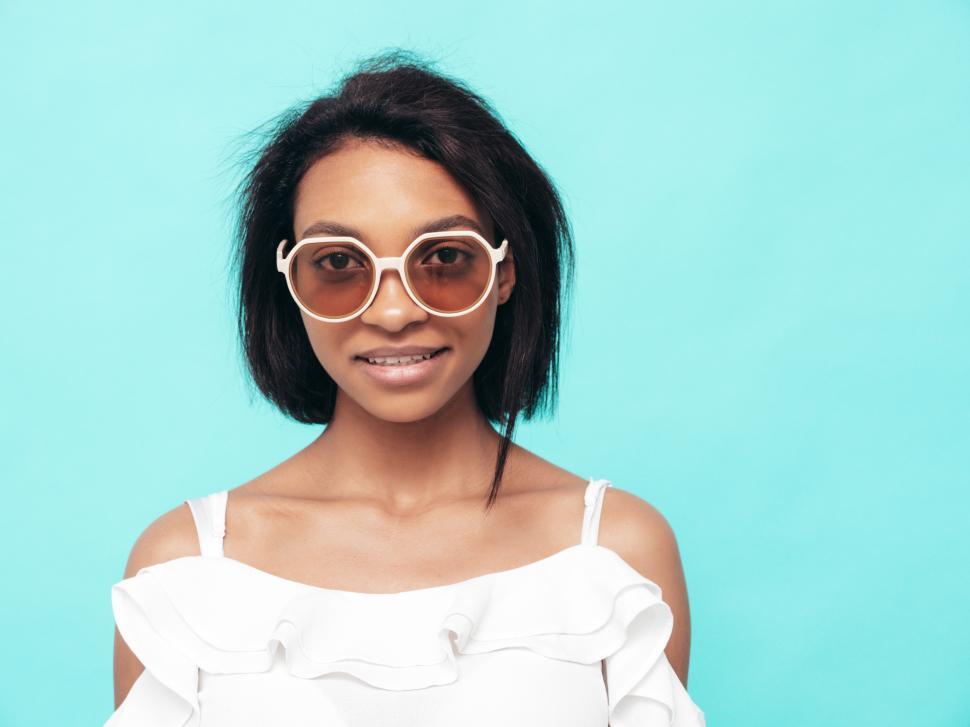 Free Image of Stylish woman in white blouse with sunglasses smiling. 
